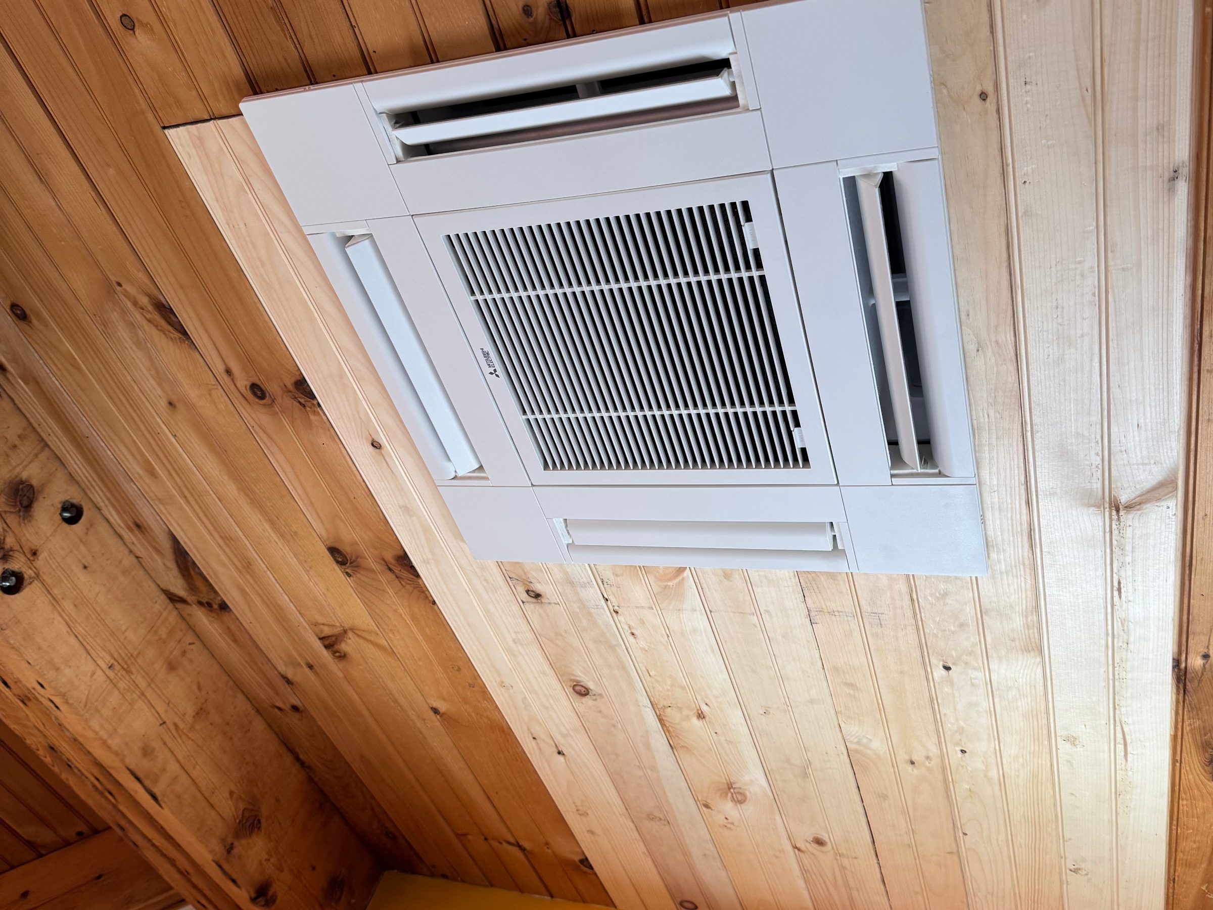 Ceiling-cassette air conditioning unit installed in a wood-panelled ceiling