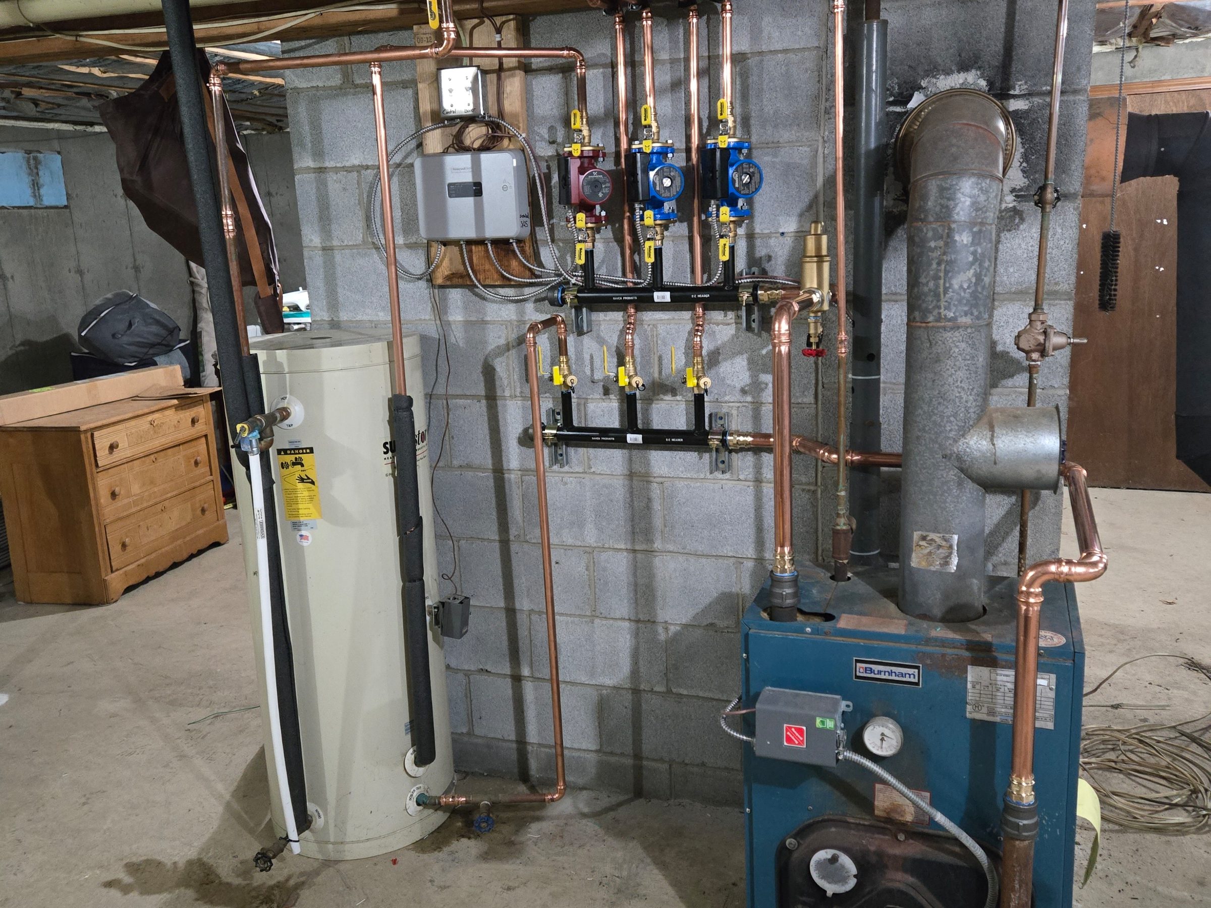 Water heater, boiler and copper pipework in a basement mechanical room